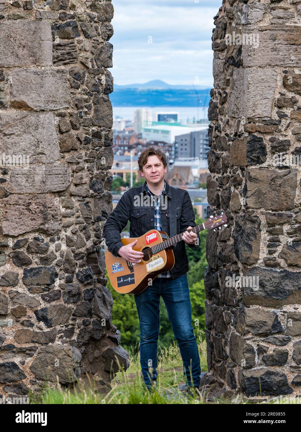 St Anthony's Chapel Holyrood Park, Édimbourg, Écosse, Royaume-Uni, 24 juillet 2023. Clip de Mike Baillie pour Fringe show : le chanteur du groupe The Lonely Together filme un nouveau clip pour son premier show Fringe Endless Sunset Oblivion qui raconte l'histoire d'un jeune compositeur Reuben qui tente de combattre les problèmes accélérés auxquels le monde est confronté. La chanson dans la vidéo a été écrite à cet endroit. Crédit : Sally Anderson/Alamy Live News Banque D'Images