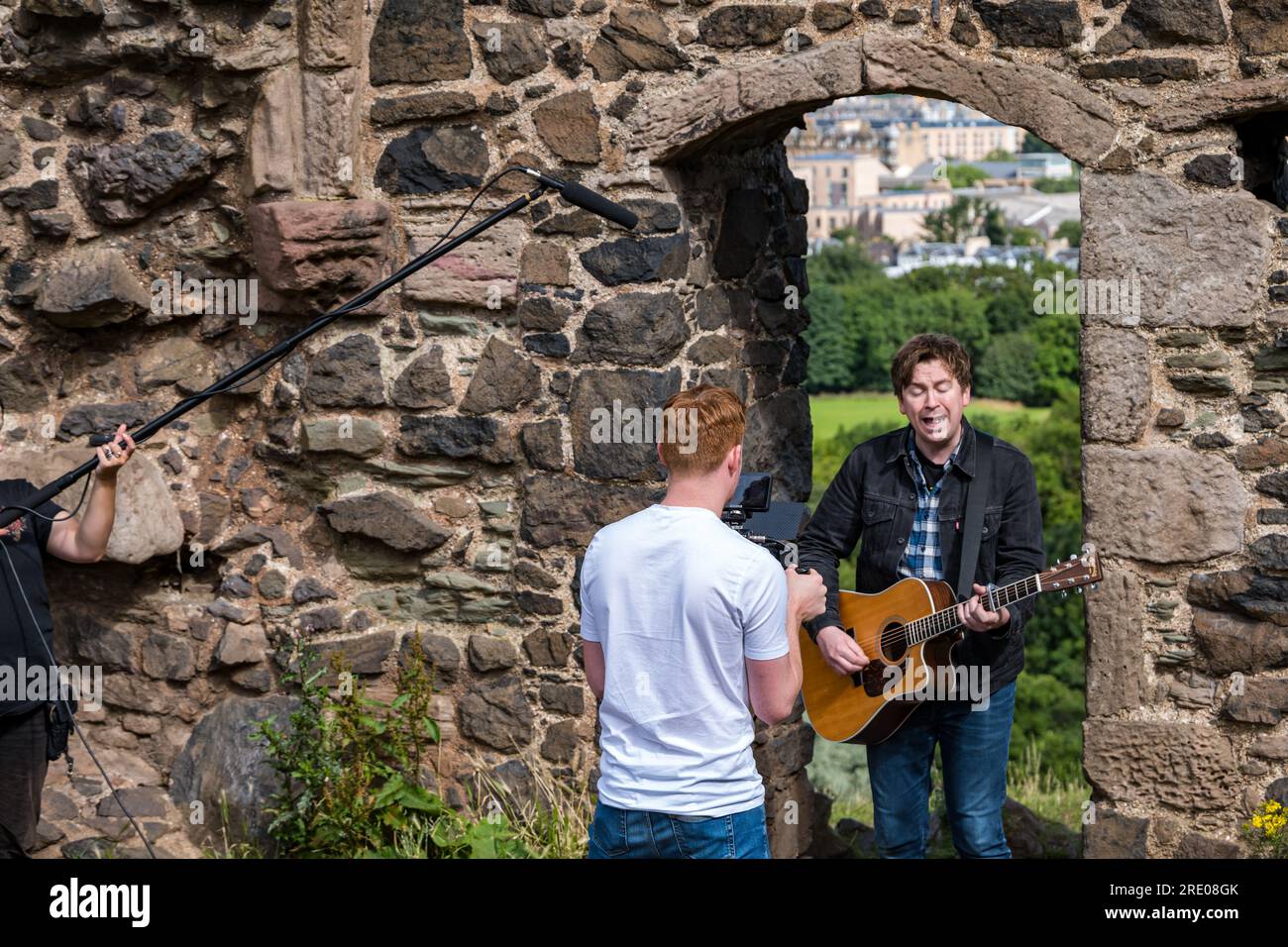 St Anthony's Chapel Holyrood Park, Édimbourg, Écosse, Royaume-Uni, 24 juillet 2023. Clip de Mike Baillie pour Fringe show : le chanteur du groupe The Lonely Together filme un nouveau clip pour son premier show Fringe Endless Sunset Oblivion qui raconte l'histoire d'un jeune compositeur Reuben qui tente de combattre les problèmes accélérés auxquels le monde est confronté. La chanson dans la vidéo a été écrite à cet endroit. Crédit : Sally Anderson/Alamy Live News Banque D'Images