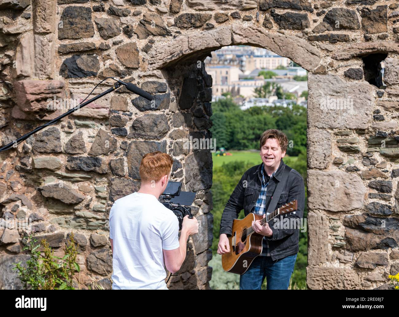 St Anthony's Chapel Holyrood Park, Édimbourg, Écosse, Royaume-Uni, 24 juillet 2023. Clip de Mike Baillie pour Fringe show : le chanteur du groupe The Lonely Together filme un nouveau clip pour son premier show Fringe Endless Sunset Oblivion qui raconte l'histoire d'un jeune compositeur Reuben qui tente de combattre les problèmes accélérés auxquels le monde est confronté. La chanson dans la vidéo a été écrite à cet endroit. Crédit : Sally Anderson/Alamy Live News Banque D'Images
