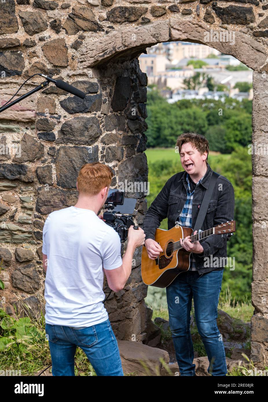 St Anthony's Chapel Holyrood Park, Édimbourg, Écosse, Royaume-Uni, 24 juillet 2023. Clip de Mike Baillie pour Fringe show : le chanteur du groupe The Lonely Together filme un nouveau clip pour son premier show Fringe Endless Sunset Oblivion qui raconte l'histoire d'un jeune compositeur Reuben qui tente de combattre les problèmes accélérés auxquels le monde est confronté. La chanson dans la vidéo a été écrite à cet endroit. Crédit : Sally Anderson/Alamy Live News Banque D'Images