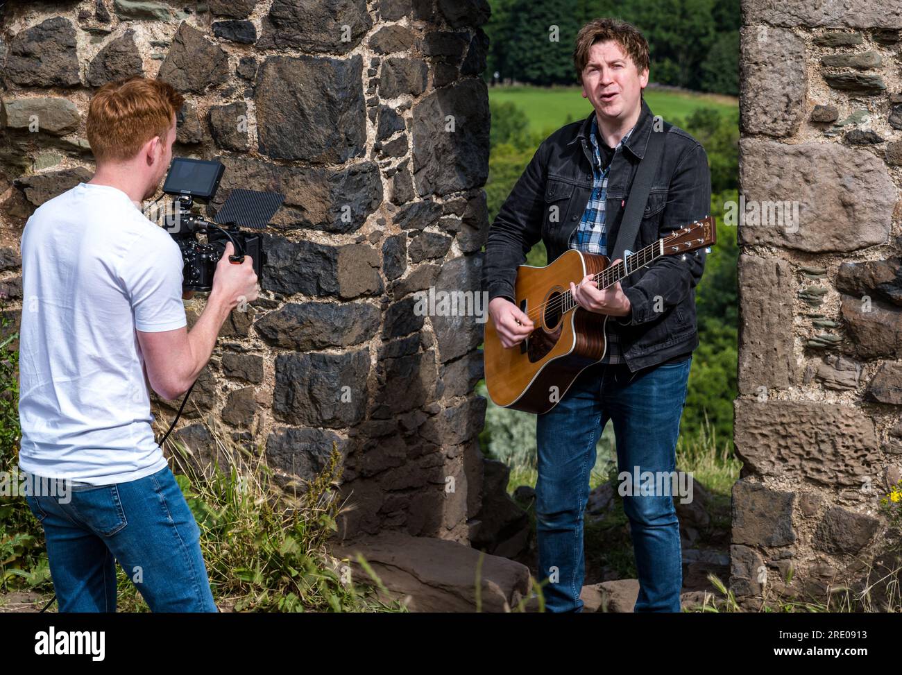 St Anthony's Chapel Holyrood Park, Édimbourg, Écosse, Royaume-Uni, 24 juillet 2023. Clip de Mike Baillie pour Fringe show : le chanteur du groupe The Lonely Together filme un nouveau clip pour son premier show Fringe Endless Sunset Oblivion qui raconte l'histoire d'un jeune compositeur Reuben qui tente de combattre les problèmes accélérés auxquels le monde est confronté. La chanson dans la vidéo a été écrite à cet endroit. Crédit : Sally Anderson/Alamy Live News Banque D'Images