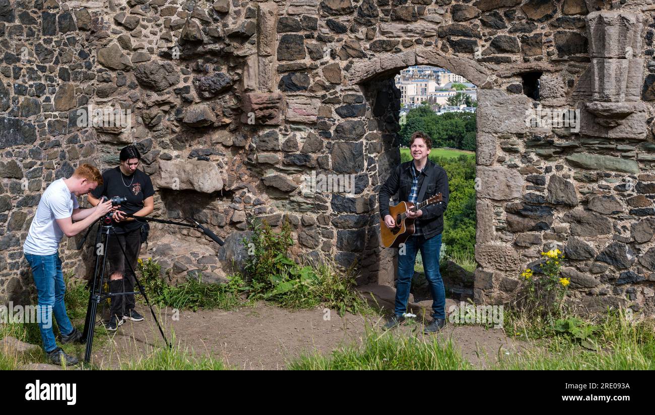 St Anthony's Chapel Holyrood Park, Édimbourg, Écosse, Royaume-Uni, 24 juillet 2023. Clip de Mike Baillie pour Fringe show : le chanteur du groupe The Lonely Together filme un nouveau clip pour son premier show Fringe Endless Sunset Oblivion qui raconte l'histoire d'un jeune compositeur Reuben qui tente de combattre les problèmes accélérés auxquels le monde est confronté. La chanson dans la vidéo a été écrite à cet endroit. Crédit : Sally Anderson/Alamy Live News Banque D'Images