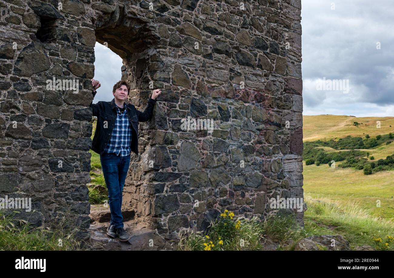 St Anthony's Chapel Holyrood Park, Édimbourg, Écosse, Royaume-Uni, 24 juillet 2023. Clip de Mike Baillie pour Fringe show : le chanteur du groupe The Lonely Together filme un nouveau clip pour son premier show Fringe Endless Sunset Oblivion qui raconte l'histoire d'un jeune compositeur Reuben qui tente de combattre les problèmes accélérés auxquels le monde est confronté. La chanson dans la vidéo a été écrite à cet endroit. Crédit : Sally Anderson/Alamy Live News Banque D'Images