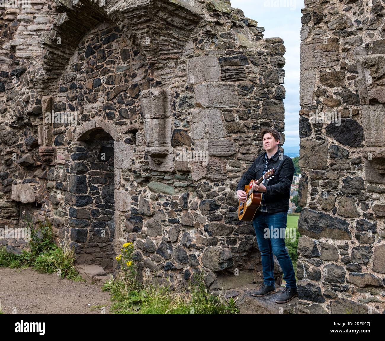 St Anthony's Chapel Holyrood Park, Édimbourg, Écosse, Royaume-Uni, 24 juillet 2023. Clip de Mike Baillie pour Fringe show : le chanteur du groupe The Lonely Together filme un nouveau clip pour son premier show Fringe Endless Sunset Oblivion qui raconte l'histoire d'un jeune compositeur Reuben qui tente de combattre les problèmes accélérés auxquels le monde est confronté. La chanson dans la vidéo a été écrite à cet endroit. Crédit : Sally Anderson/Alamy Live News Banque D'Images