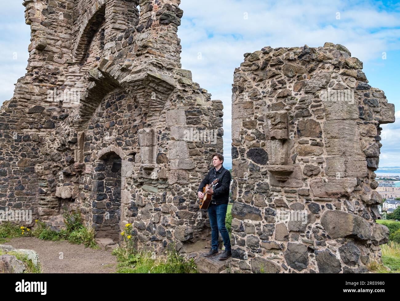 St Anthony's Chapel Holyrood Park, Édimbourg, Écosse, Royaume-Uni, 24 juillet 2023. Clip de Mike Baillie pour Fringe show : le chanteur du groupe The Lonely Together filme un nouveau clip pour son premier show Fringe Endless Sunset Oblivion qui raconte l'histoire d'un jeune compositeur Reuben qui tente de combattre les problèmes accélérés auxquels le monde est confronté. La chanson dans la vidéo a été écrite à cet endroit. Crédit : Sally Anderson/Alamy Live News Banque D'Images