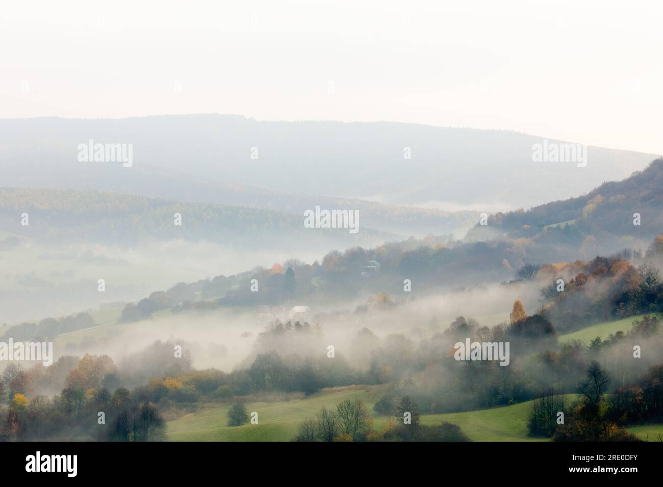 Paysage rural de montagne d'automne avec forêt. Matin brumeux. Brouillard épais roulant dans une vallée avec de petites maisons. Ciel nuageux. Vue de dessus, Horna Suca, Slovaquie Banque D'Images