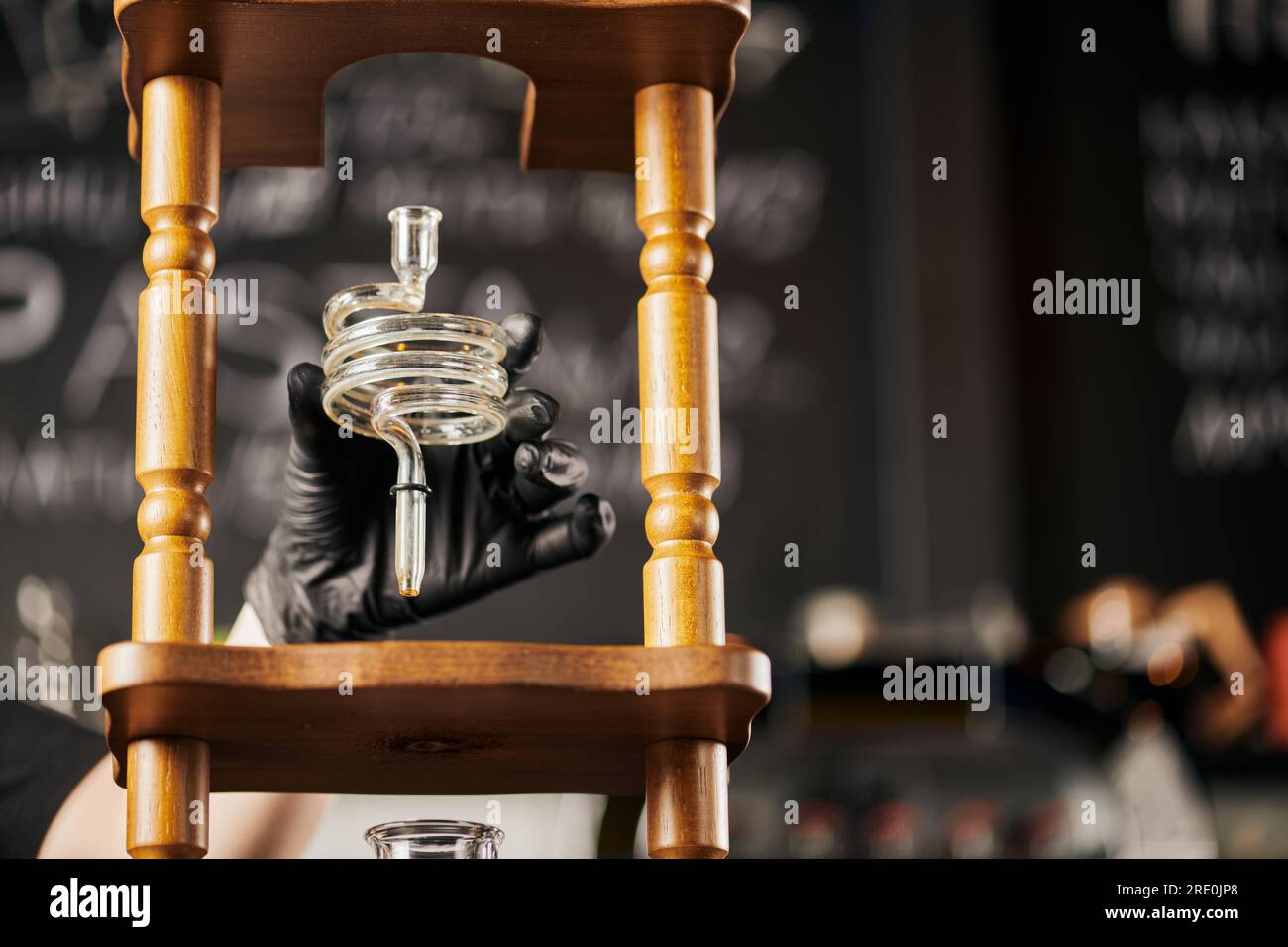 barista en gant en latex noir tenant la partie en spirale de la cafetière d'infusion à froid, méthode alternative Banque D'Images