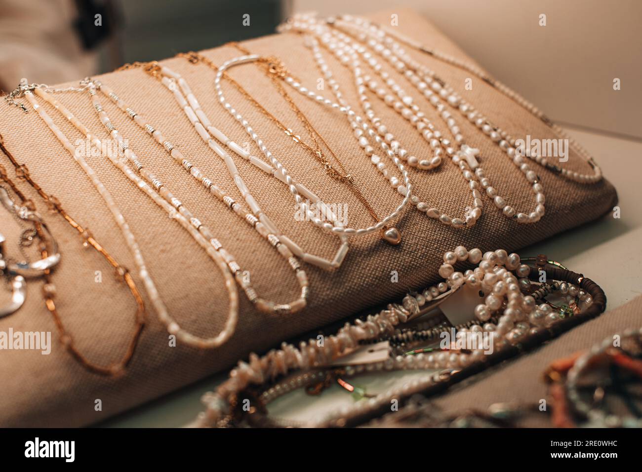 Perles de bijoux en perles blanches et chaînes dorées. Collier sur la vitrine du magasin d'accessoires pour femmes Banque D'Images