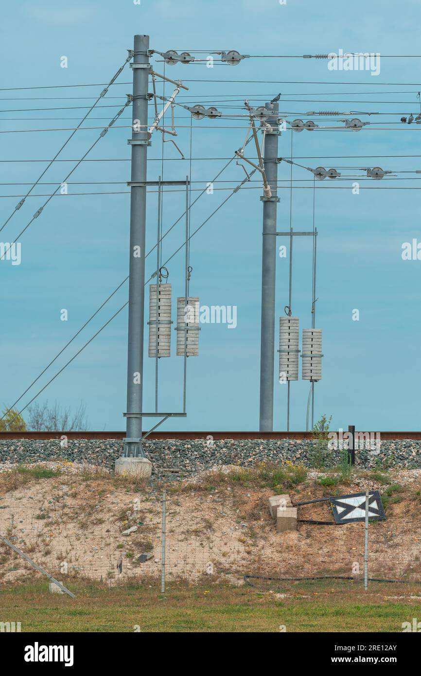 Pôle de tension de ligne de chemin de fer électrique avec fils et poids en béton, mise au point sélective Banque D'Images