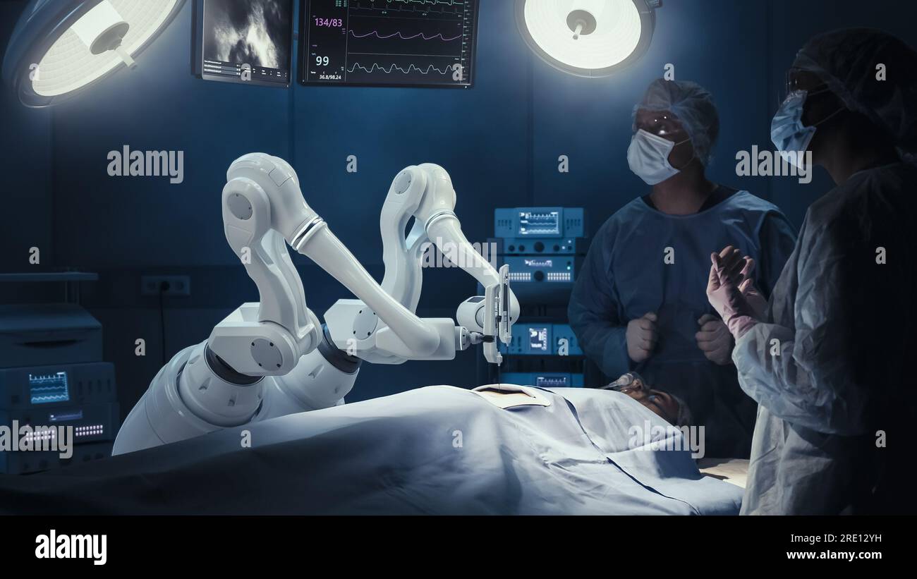 Deux chirurgiens observant des bras robotiques automatisés programmables de haute précision opérant un patient dans un hôpital de haute technologie. Membres robotisés pratiquant la chirurgie Banque D'Images