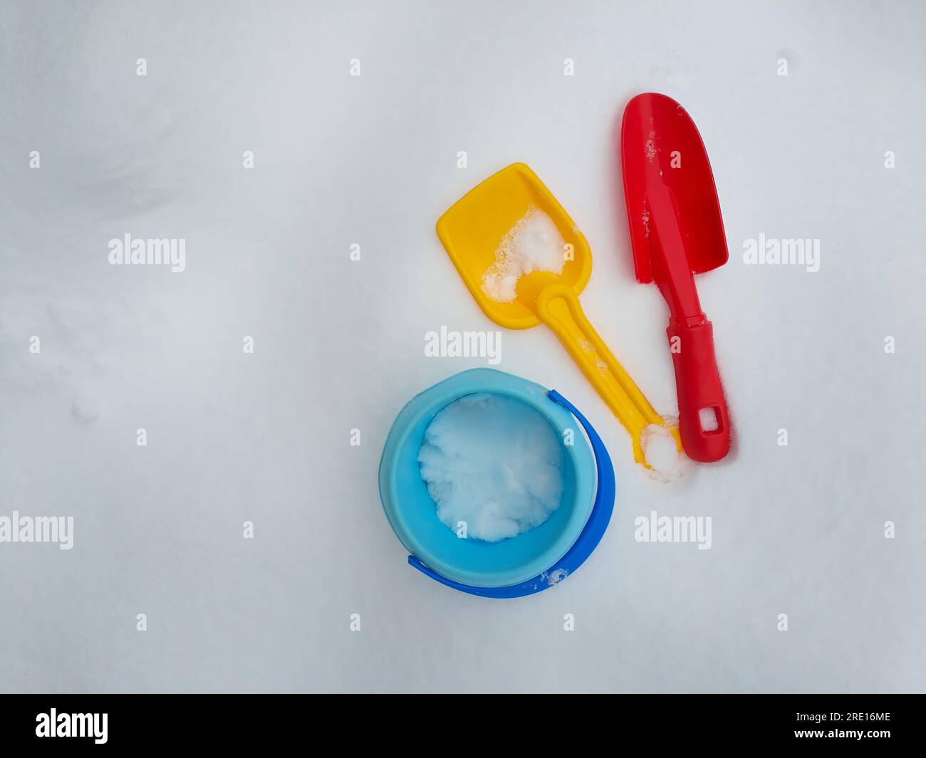 Jouets pour enfants en plastique coloré dans le terrain de jeu de neige blanche d'hiver, pelle, truelle, pelle, seau, vue grand angle, espace de copie Banque D'Images