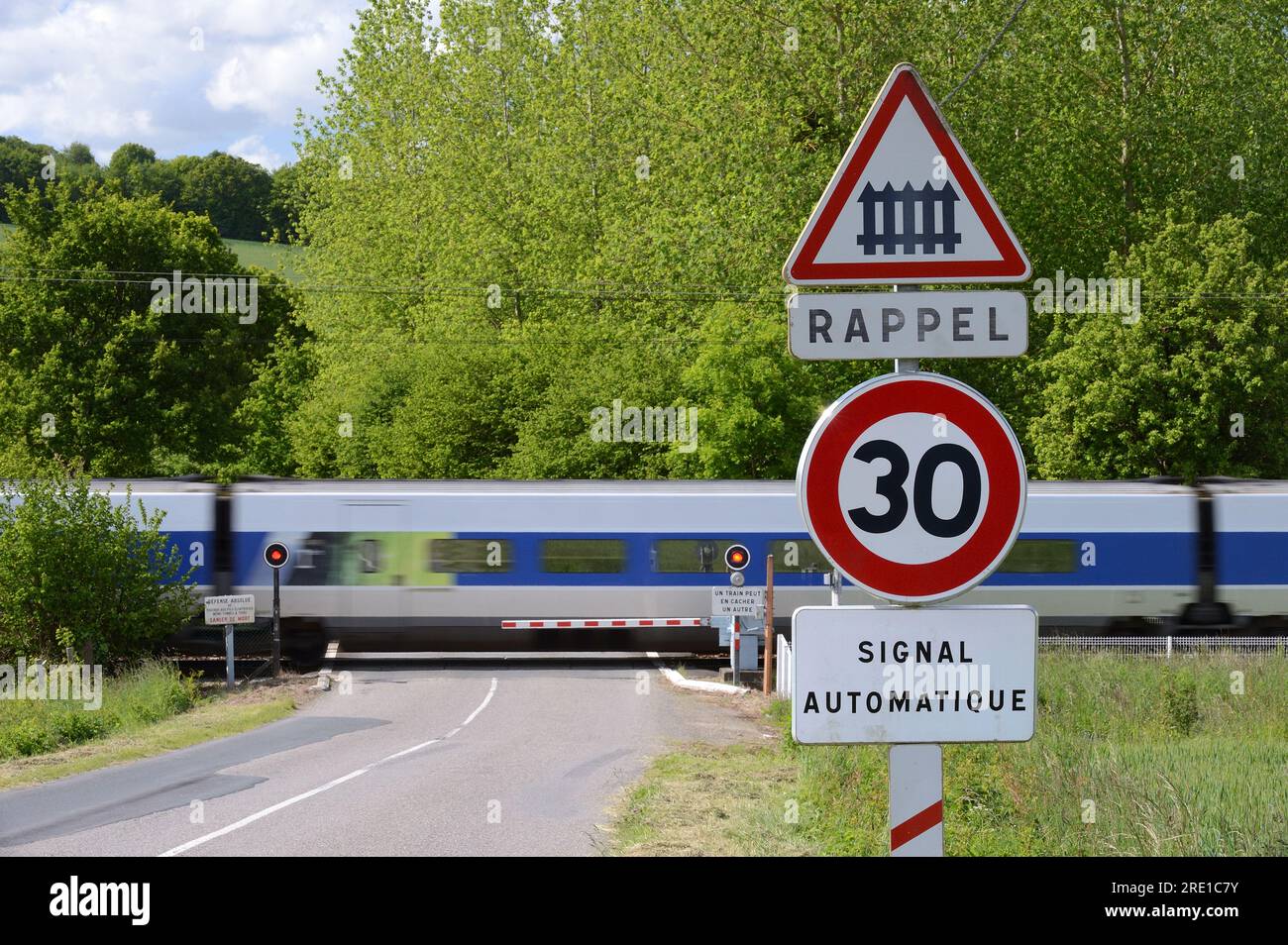 Passage à niveau sur une route de campagne avec portail ferroviaire automatique. Panneau de passage à niveau, limite de vitesse de 30 km/h. Banque D'Images