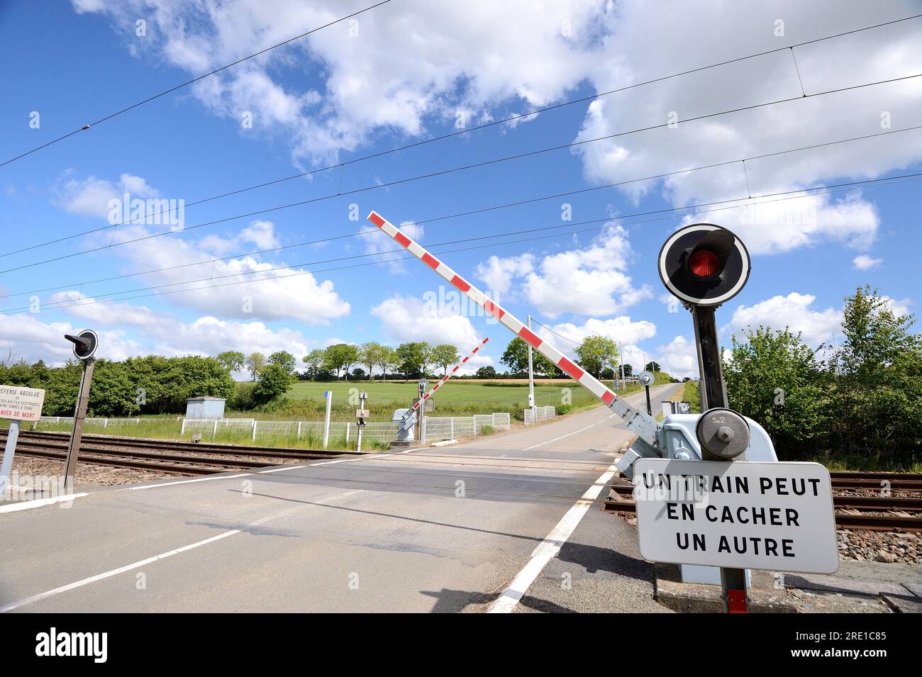 Passage à niveau sur une route de campagne avec portail ferroviaire automatique. Fermeture automatique des portes, portes abaissées et voyant rouge clignotant avant qu'un train ne passe Banque D'Images