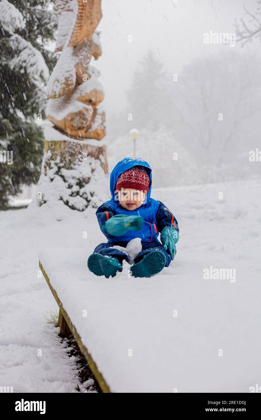 bébé de 11 mois assis dans la neige portant une combinaison de neige Banque D'Images