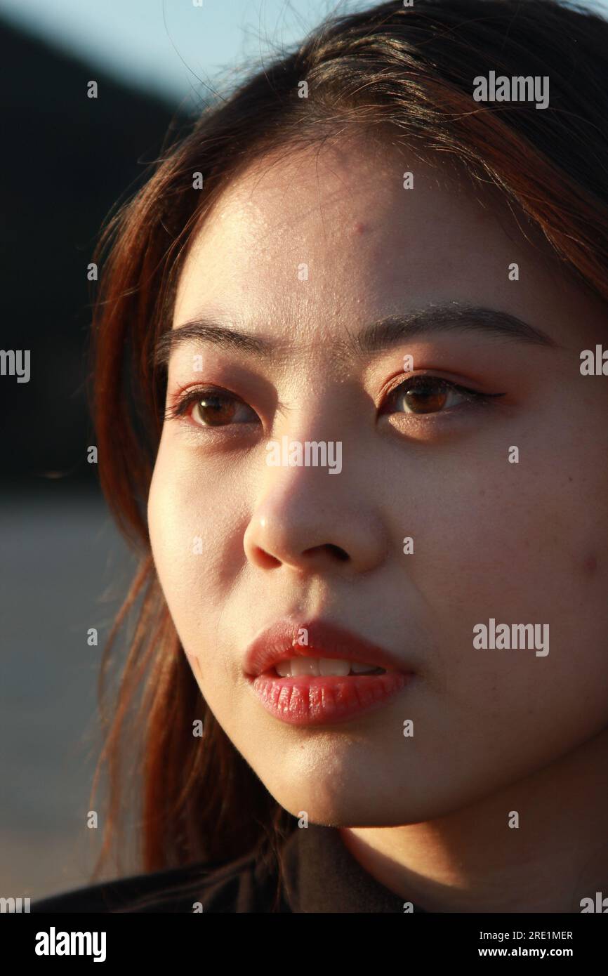 Portrait de fille dans l'heure d'or, les yeux bruns rencontrent la lumière du soleil. Banque D'Images