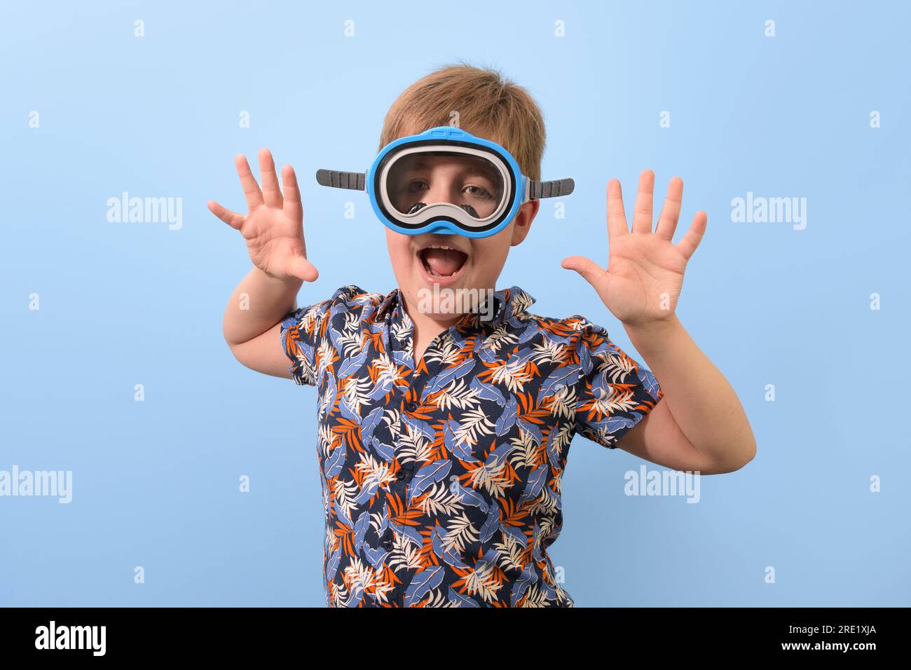 Un garçon dans un masque de plongée dans une chemise hawaïenne démontre des réjouissances dans les vacances Banque D'Images