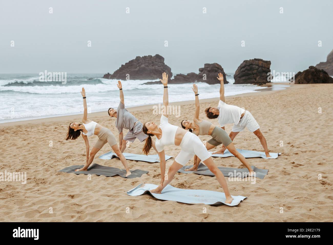 Entraînement matinal. Groupe de jeunes pratiquant le yoga sur la plage, méditant et faisant de l'exercice sur la rive de l'océan Banque D'Images
