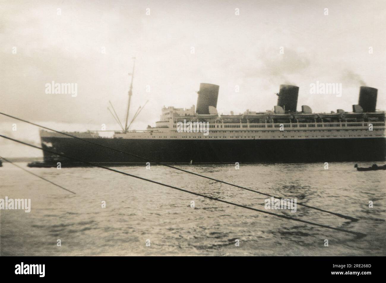 Southampton, Hampshire. c.1938 – le paquebot transatlantique Cunard-White Star Line, RMS Queen Mary, est manœuvré hors des quais de Southampton par un remorqueur. Le navire a été construit par John Brown & Company à Clydebank, en Écosse et a navigué pour son voyage inaugural le 27 mai 1936. En dehors d'une période de la Seconde Guerre mondiale, où il est converti et employé comme navire de troupe, il reste en service jusqu'en 1967. Elle remporte le prix Blue Riband de la traversée transatlantique la plus rapide en août 1936, puis de nouveau en 1938, le conservant jusqu'en 1952. Banque D'Images