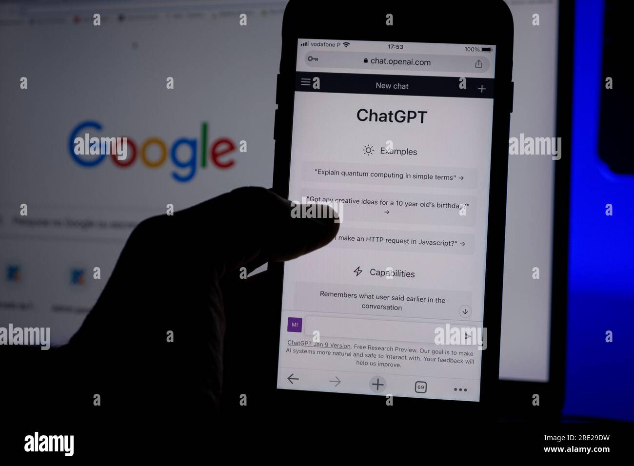 Açores, Portugal - 16.01.2023 : téléphone portable à main levée avec ai ChatGPT page d'accueil. Développé par OpenAI. En arrière-plan, un écran d'ordinateur portable avec effet de flou artistique Banque D'Images