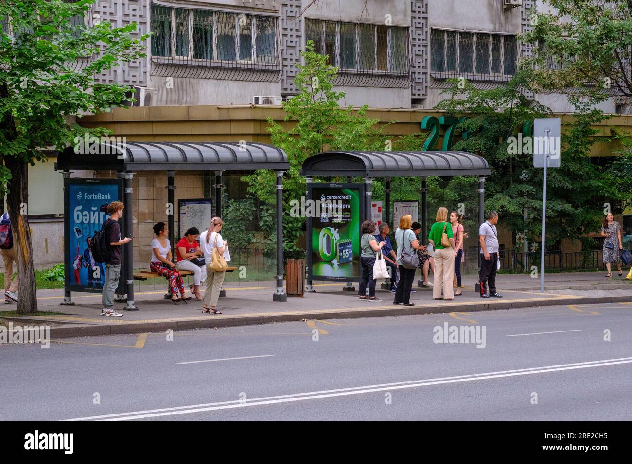 Kazakhstan, Almaty. Scène de rue : passagers attendant le bus à l'arrêt de bus. Banque D'Images