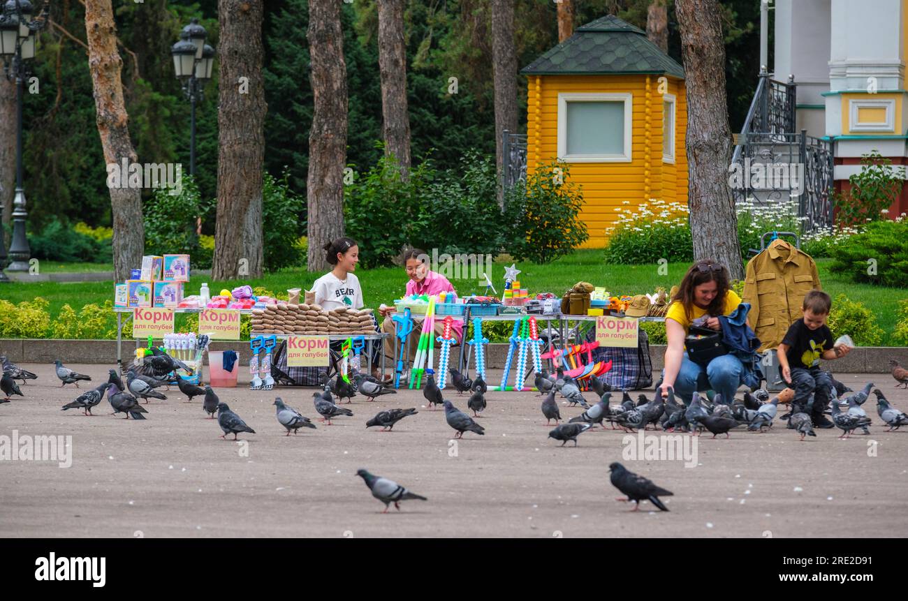 Kazakhstan, Almaty. Nourrir les pigeons devant la cathédrale de l'Ascension, Panfilov Guardsmen Park. Banque D'Images