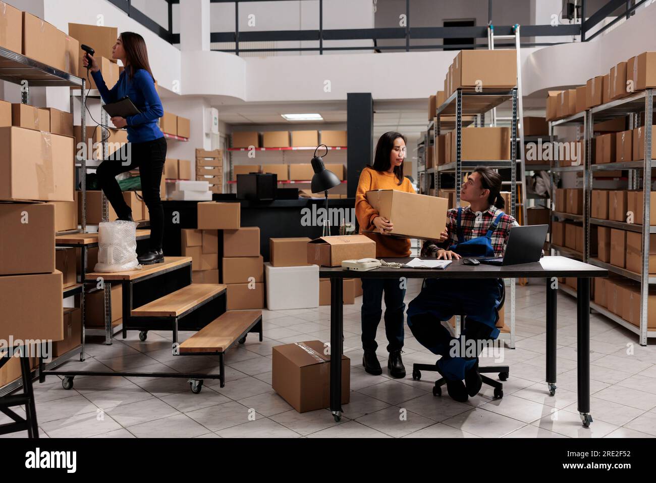 Les employés d'entrepôt font le contrôle de la qualité des colis et stockent l'inventaire sur ordinateur portable. Storehouse asiatique homme et femme équipe travaillant dans la salle de stockage pleine d'étagères avec des boîtes en carton Banque D'Images