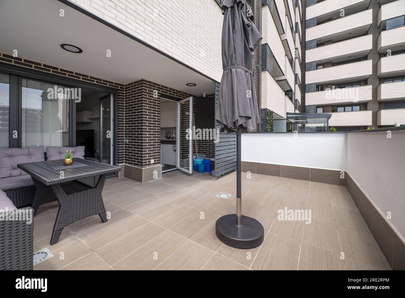 solarium terrasse d'une maison avec planchers en bois terrazzo gris, table en rotin synthétique et coin du même matériau et coussins gris et f assorti Banque D'Images