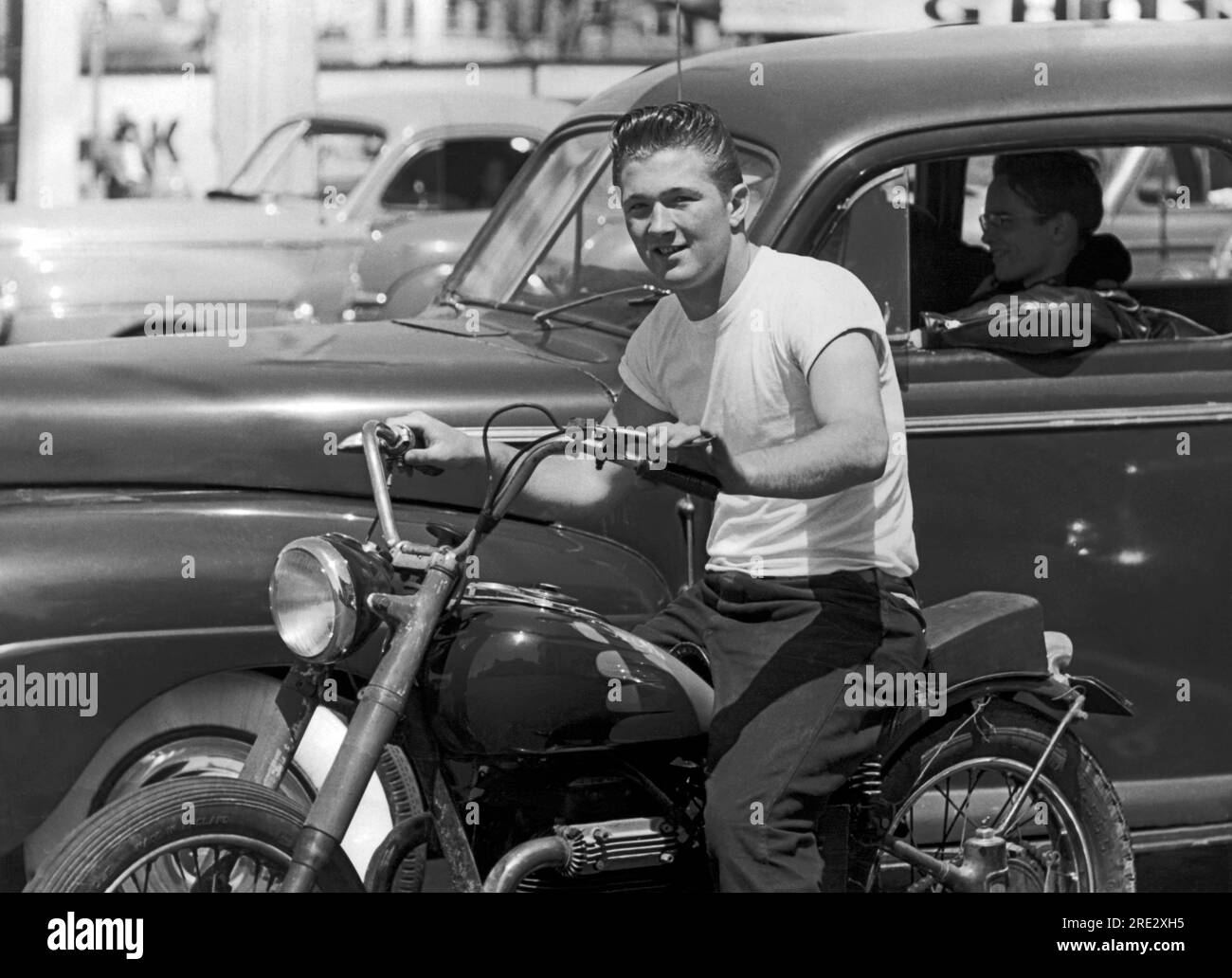 San Francisco, Californie : c. 1955 Un jeune homme sur une moto à côté de son copain portant une veste en cuir dans une voiture Banque D'Images