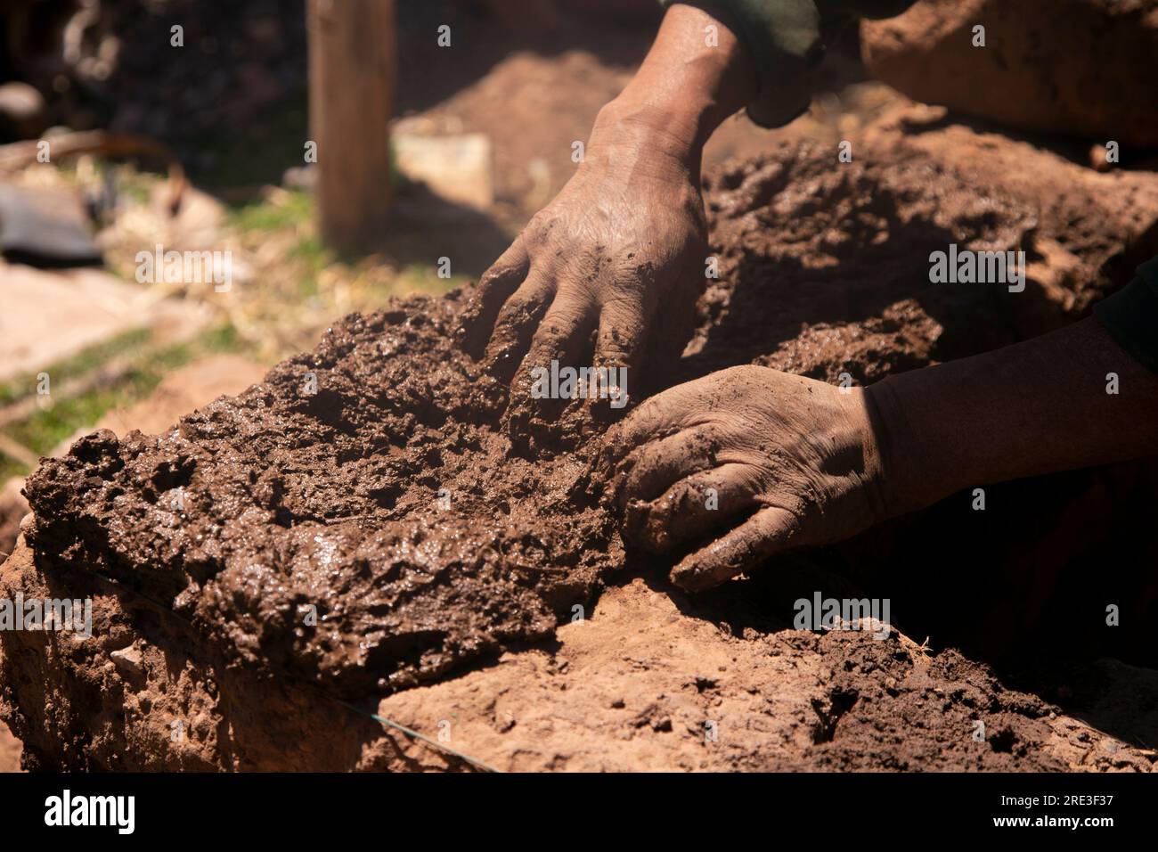 Homme construisant avec ses mains une maison en adobe avec des briques en adobe et de la boue. Région de Llachon du lac Titicaca au Pérou. Banque D'Images