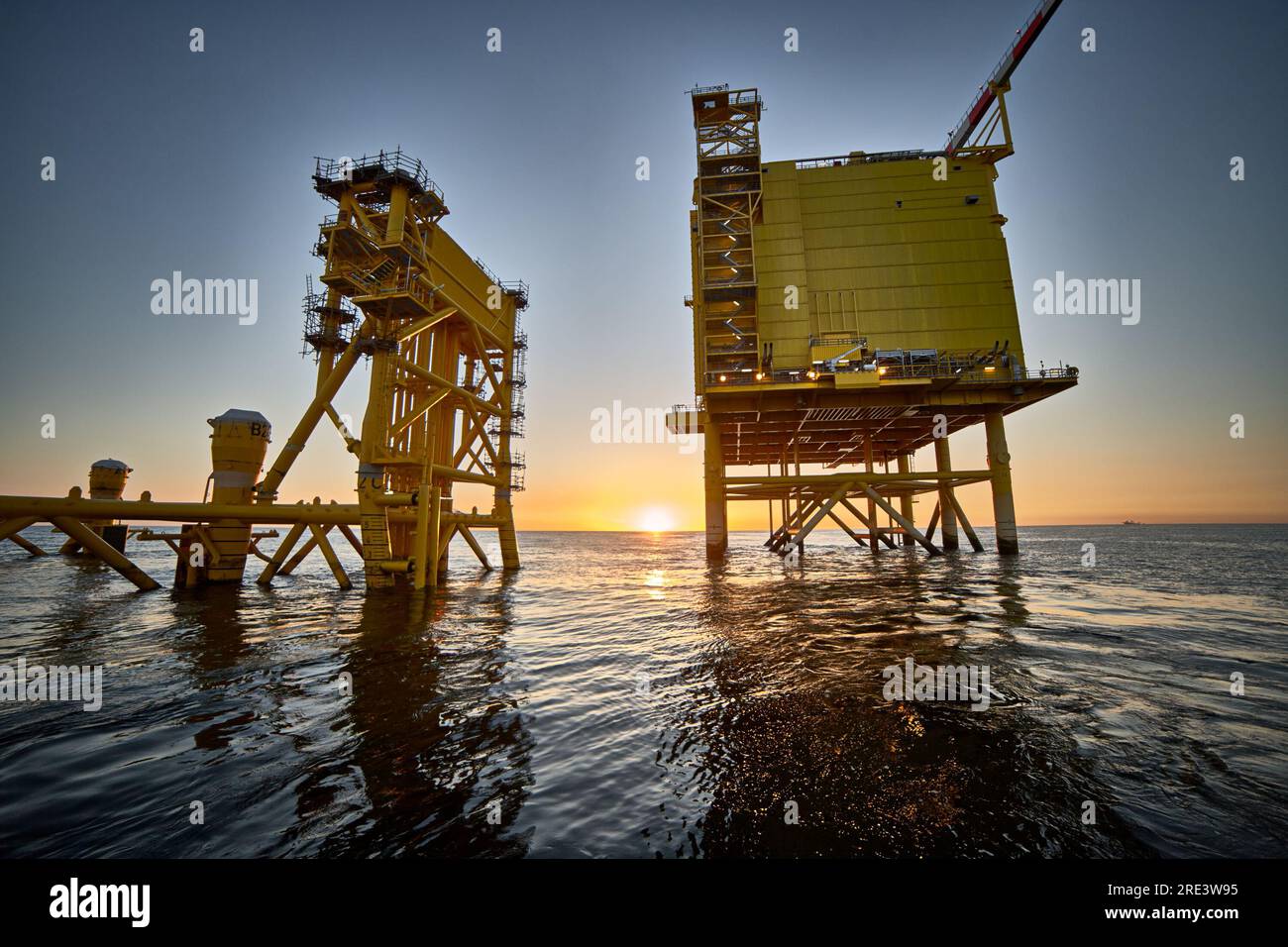 Vue de la station de distribution électrique offshore pour les parcs éoliens au coucher du soleil en mer. Banque D'Images
