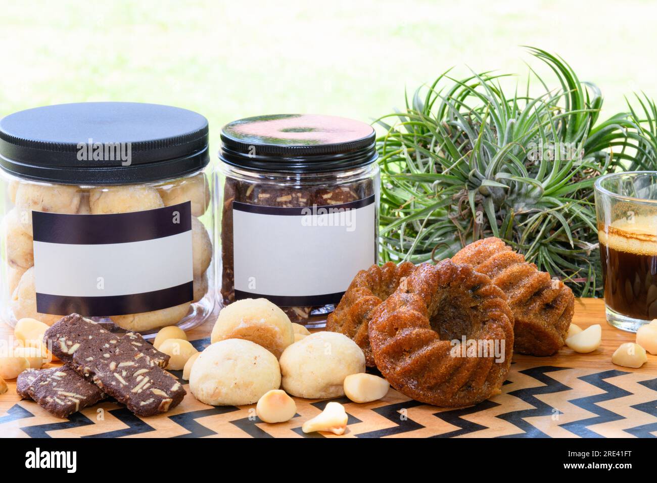 Noix de macadamia et biscuits dans une boîte en plastique à côté d'une tasse de café noir sur une table en bois dans la cour arrière Banque D'Images