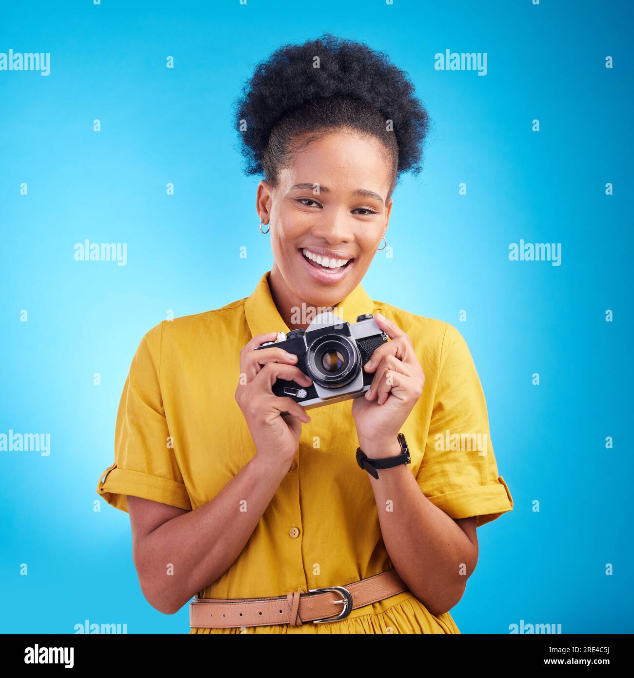 Photographie, portrait et femme noire avec appareil photo, sourire et isolé sur fond bleu, travail d'artiste créatif et talent. Art, visage de heureux Banque D'Images