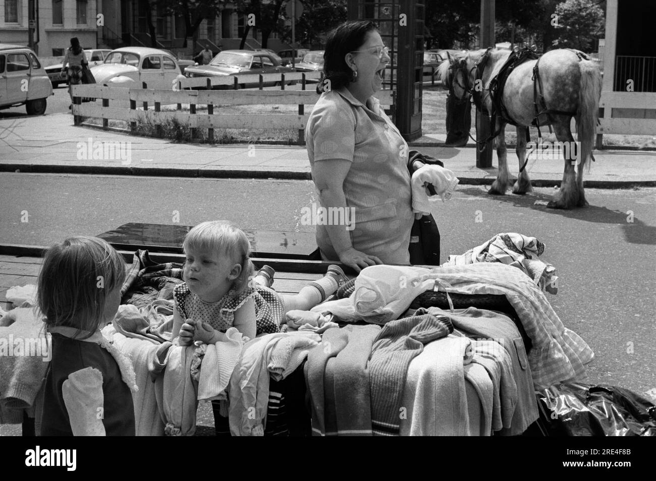 Portobello Road, marché du samedi, Notting Hill West London 1970s. Le bout haut et bon marché de la route. Vieux vêtements vendus par mère avec ses deux enfants. Cheval gitan en arrière-plan. Angleterre. ANNÉES 1975 70 ROYAUME-UNI HOMER SYKES Banque D'Images