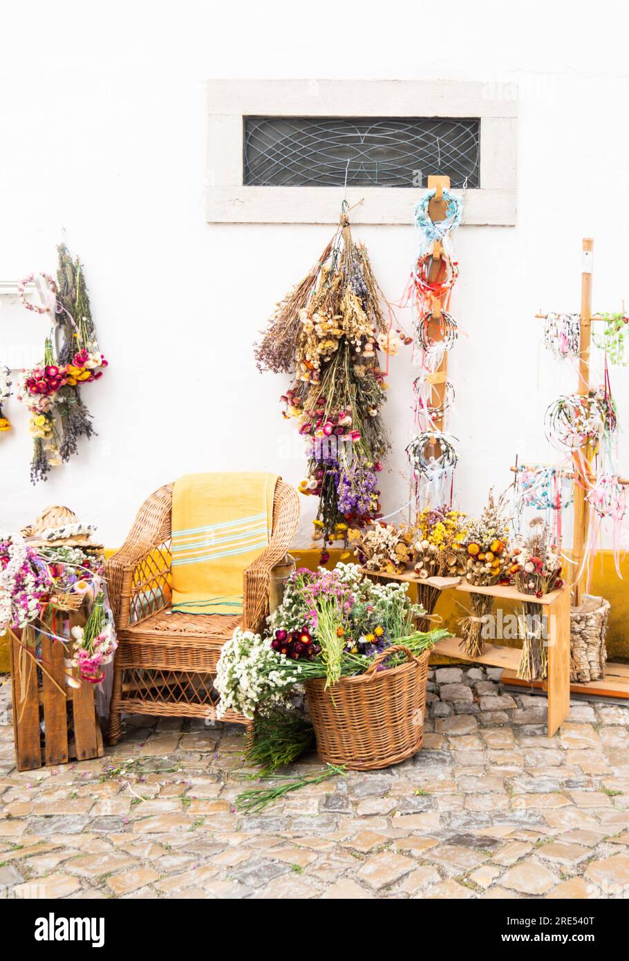 Fleuriste extérieur avec exposition sur le trottoir avec chaise en osier et paniers de fleurs fraîches et sèches Banque D'Images