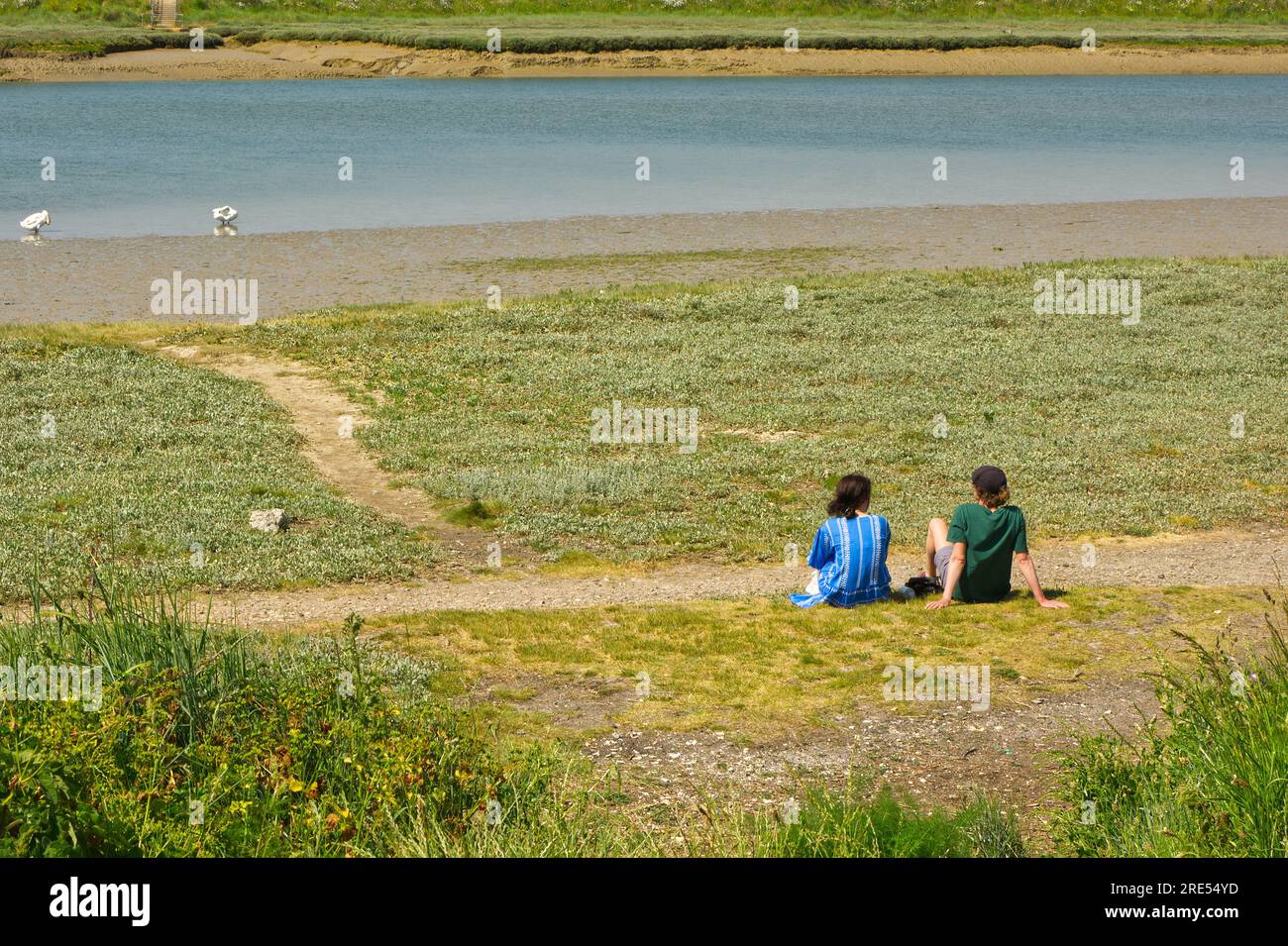 Deux jeunes femmes assises près de River Adur à Shoreham dans le West Sussex, en Angleterre. Méconnaissable. Banque D'Images