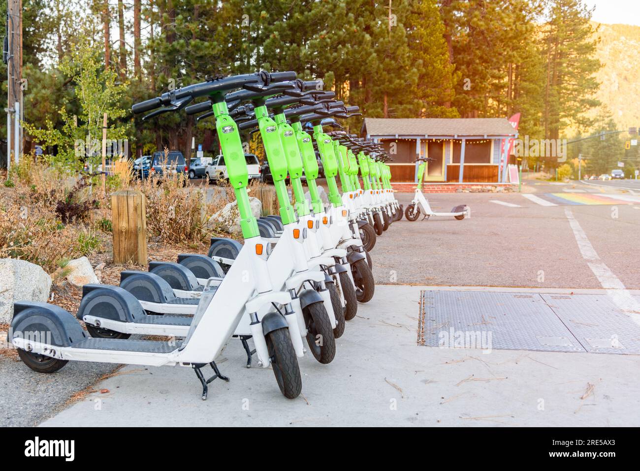 Rangée de scooters électriques à partager le long d'une rue dans une station de montagne au coucher du soleil en automne Banque D'Images