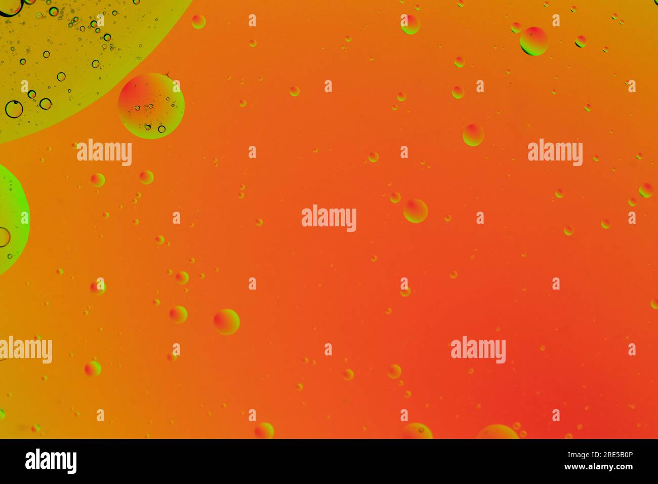 Fond orange abstrait avec des bulles jaunes en haut à gauche. Cercles organiques parfaits faits avec de l'huile dans l'eau. Simulation d'un système cellulaire et d'une image spatiale Banque D'Images