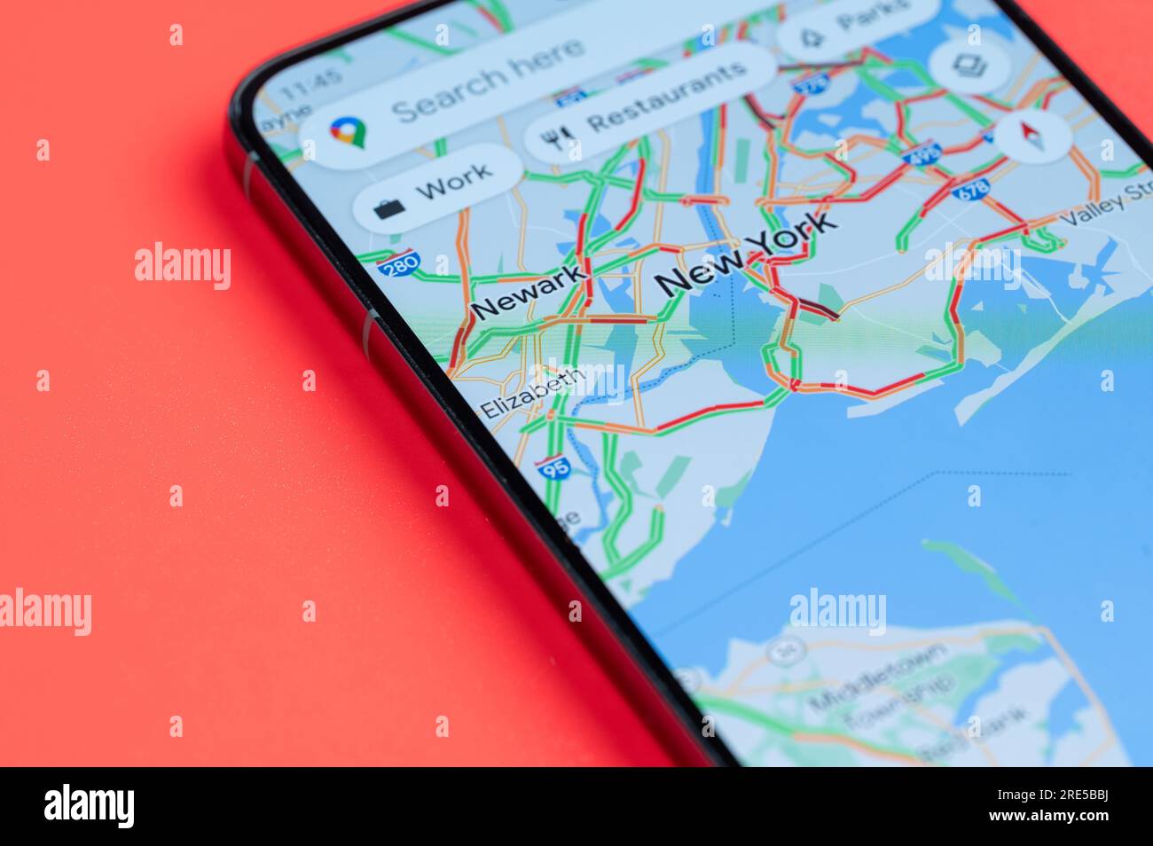 New York, USA - 21 juillet 2023 : trafic automobile sur New York google Maps sur écran smartphone vue rapprochée avec fond rouge Banque D'Images