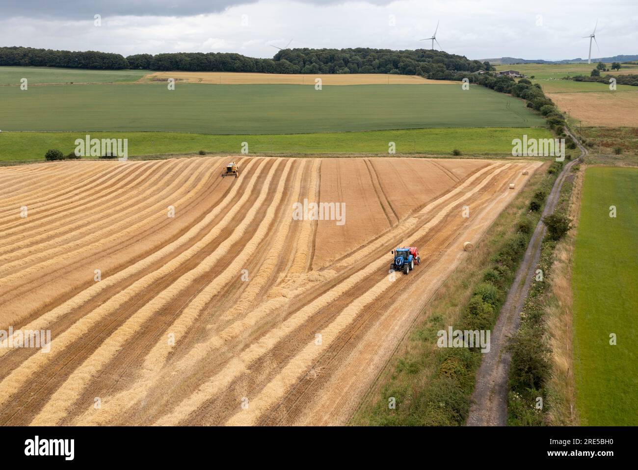 Vue aérienne par drone d'une ramasseuse-presse et d'une moissonneuse-batteuse récoltant une récolte près de Cardenden, Fife, Écosse. Banque D'Images