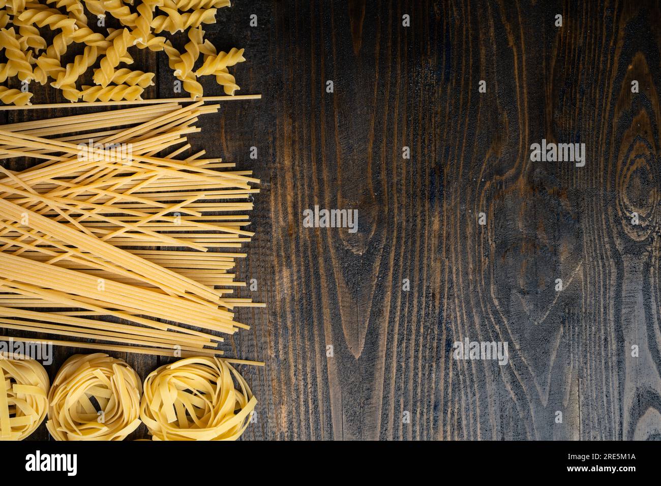 Formes de pâtes, spaghetti, fusilli, tagliatelles, ingrédients de la cuisine italienne sur fond de bois Banque D'Images