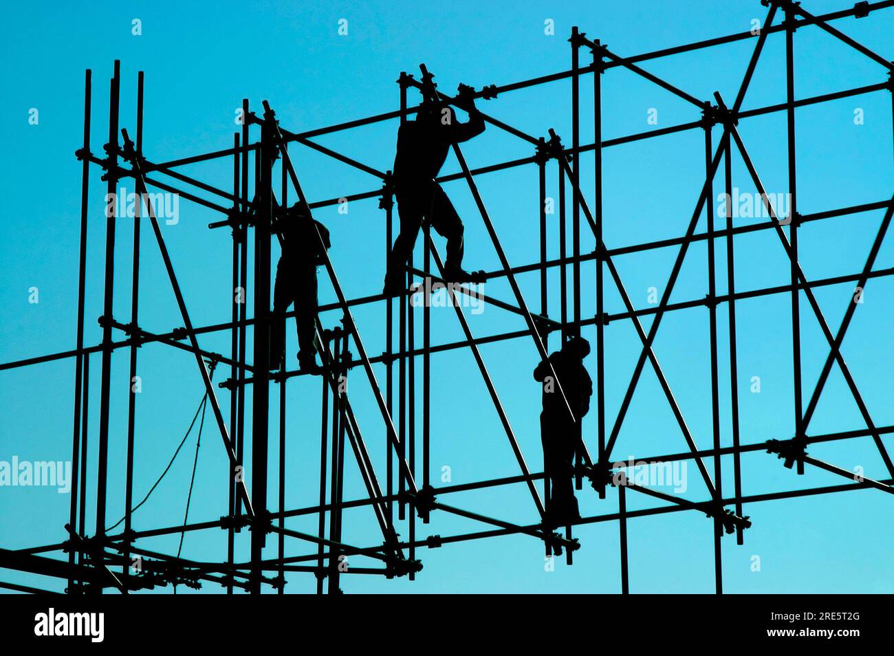La lumière du soleil du matin silhouettes trois travailleurs de la construction comme ils l'équilibre sur les tuyaux d'une nouvelle construction dans la ville de Mexico, Mexique. Banque D'Images
