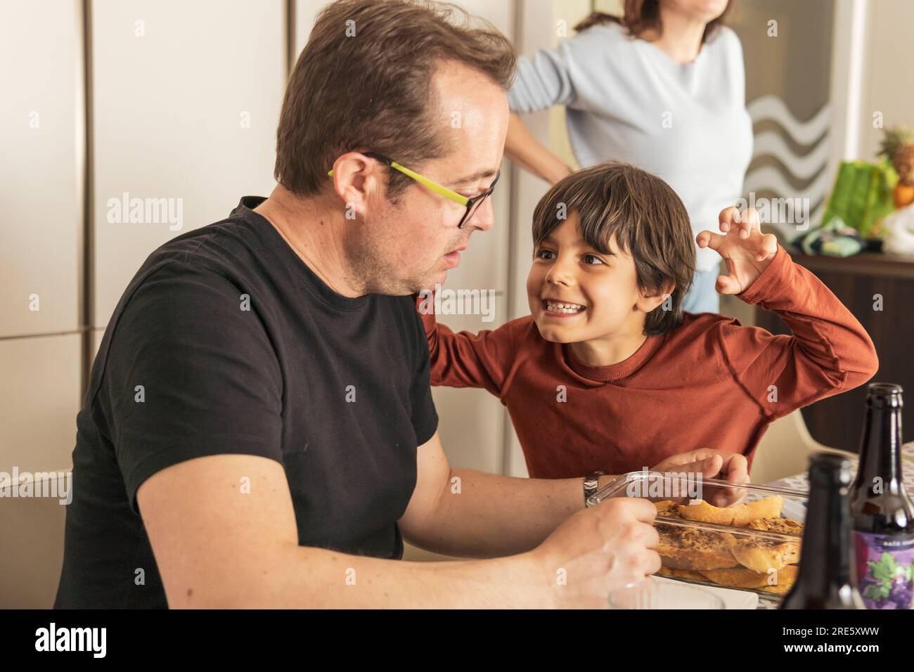 garçon jouant effrayer sa famille dans la cuisine Banque D'Images