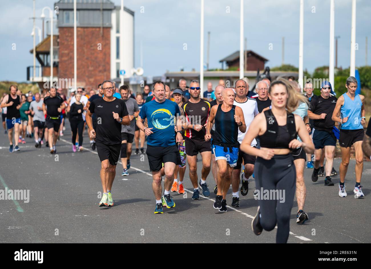 Coureurs à l'hebdomadaire Parkrun (Park Run), un événement communautaire, courant le long de la promenade du front de mer à Littlehampton, West Sussex, Angleterre, Royaume-Uni. Banque D'Images