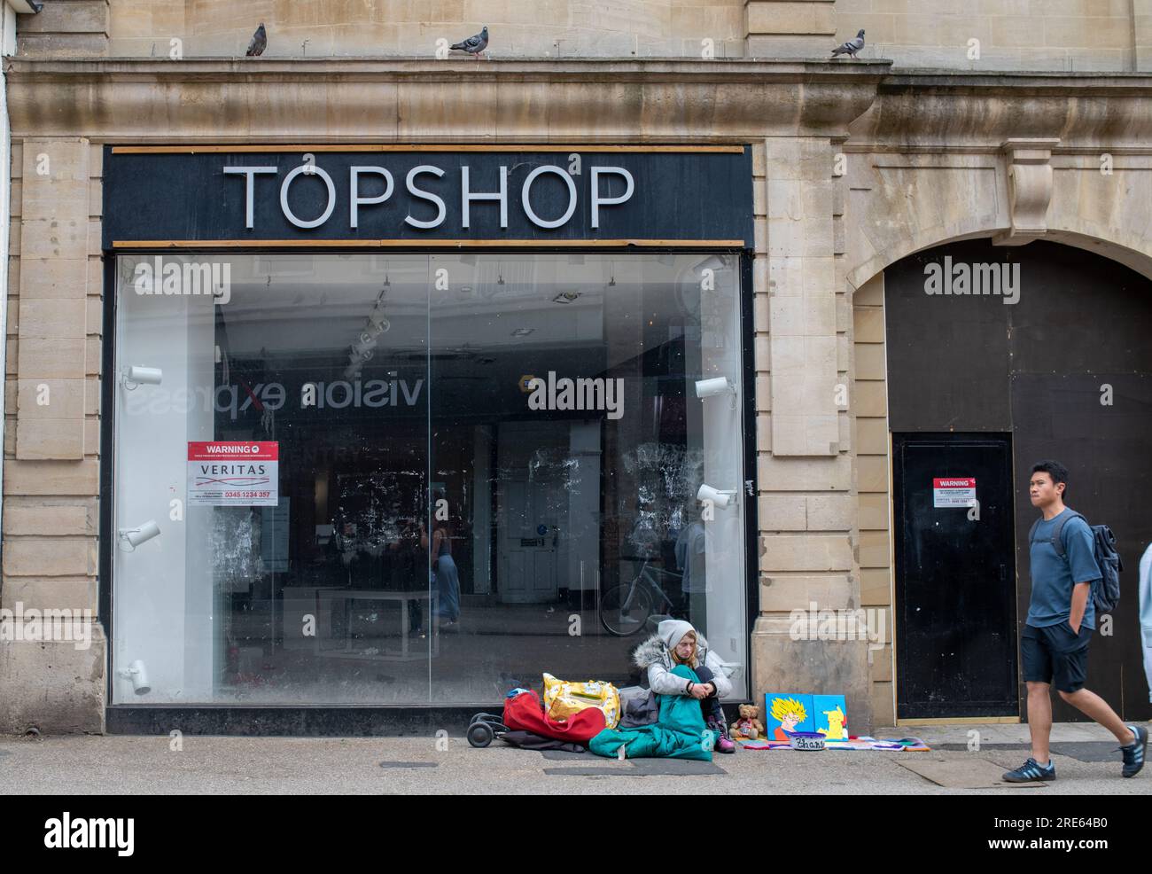 Personne sans abri assis devant le Shut-Down Top Shop, dans le centre-ville d'Oxford Banque D'Images