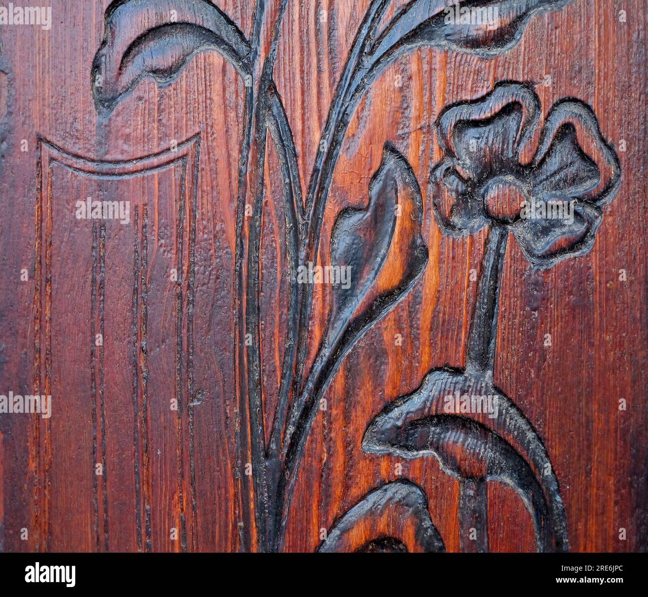 Design floral minimaliste simple avec des feuilles d'arabesque et une fleur de style art déco, un relief sculpté dans un panneau de bois huilé foncé. Banque D'Images