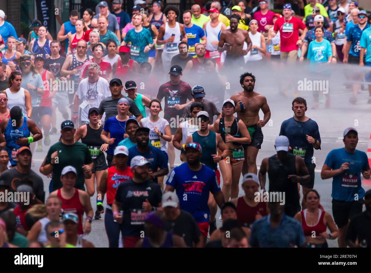 Atlanta, GA / États-Unis - 4 juillet 2023 : des milliers de coureurs courent à travers une brumeuse brumeuse de refroidissement à la Peachtree Road Race le 4 juillet 2023 à Atlanta, GA. Banque D'Images