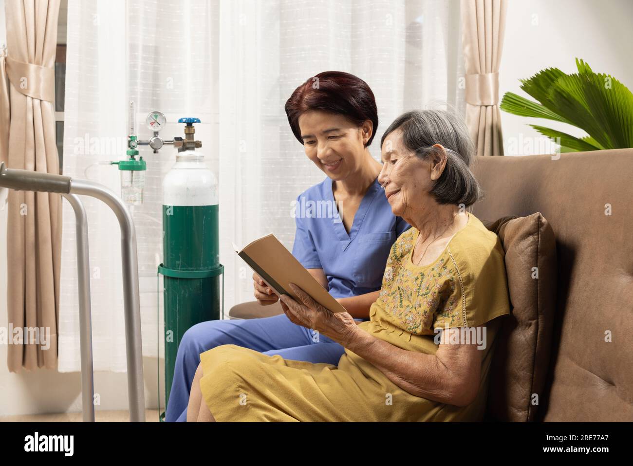 Le soignant prend soin de la femme âgée tout en portant la canule nasale d'oxygène à la maison. Banque D'Images