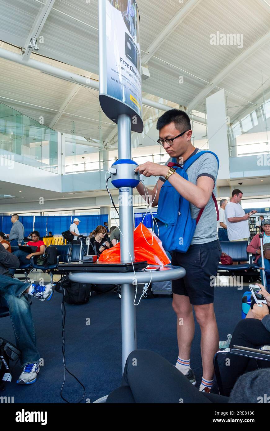 Aéroport international de Newark Liberty, NJ, États-Unis, Chinois Tourist recharge Smart Phone avec chargeur foule personnes voyageant à l'intérieur, installations de vol Banque D'Images