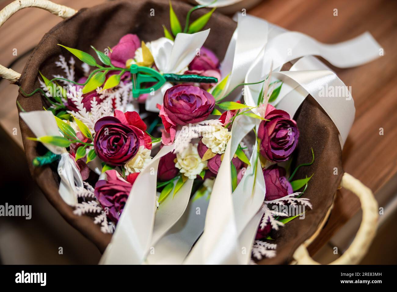 Décoration de mariage. Bracelets de fleurs roses et violettes et badges dans un panier en bois pour les invités du mariage. Photo de haute qualité Banque D'Images