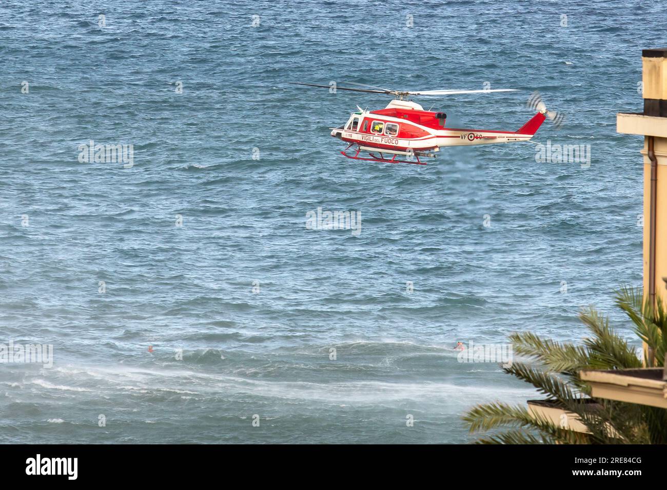 Les nageurs de sauvetage en hélicoptère de Vigili del Fuoco assistent un groupe de nageurs incautieux qui ont été emmenés par la mer agitée et les soulèvent par treuil sur leur hélicoptère. Banque D'Images